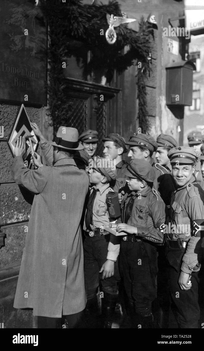 Members of the Hitlerjugend with a contributor for the Winter Relief, who may hit a nail in the coat of arms of the Hitler Youth. (Undated photo) Stock Photo