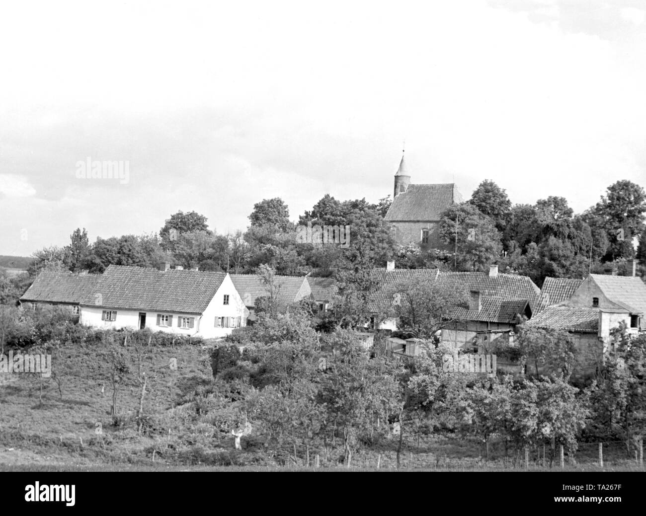 Christburg in West Prussia, small orchards and houses, in the background a small church. Stock Photo