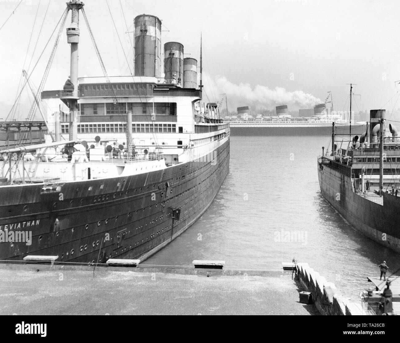 The French ocean liner 'Normandie' passes by the berth of 'Leviathan' in New York City. Both liners were the biggest ships in the world at the time of their entry into service. Stock Photo