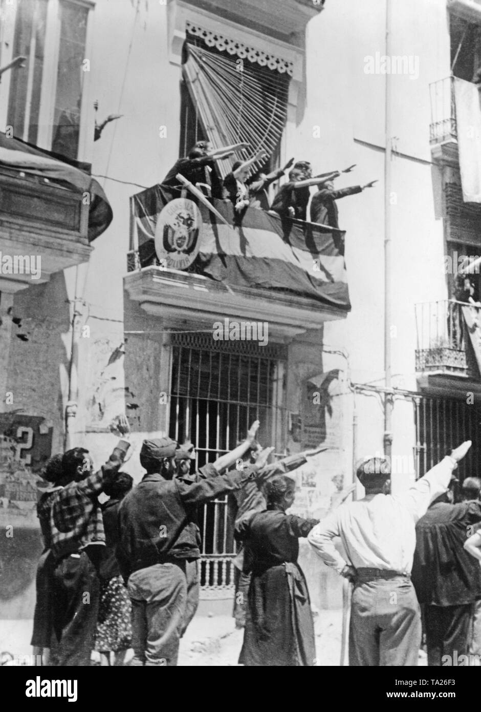 Photo of the dwellers of Castellon de la Plana, Valencia, Spain, in the evening of the 13th of June, 1936, when the Franco troops invaded the provincial capital after heavy fighting. On the street and from a flagged balcony, the inhabitants give the soldiers the Fascist salute. On the balcony, the coat of arms of a consulate of Bolivia. Stock Photo