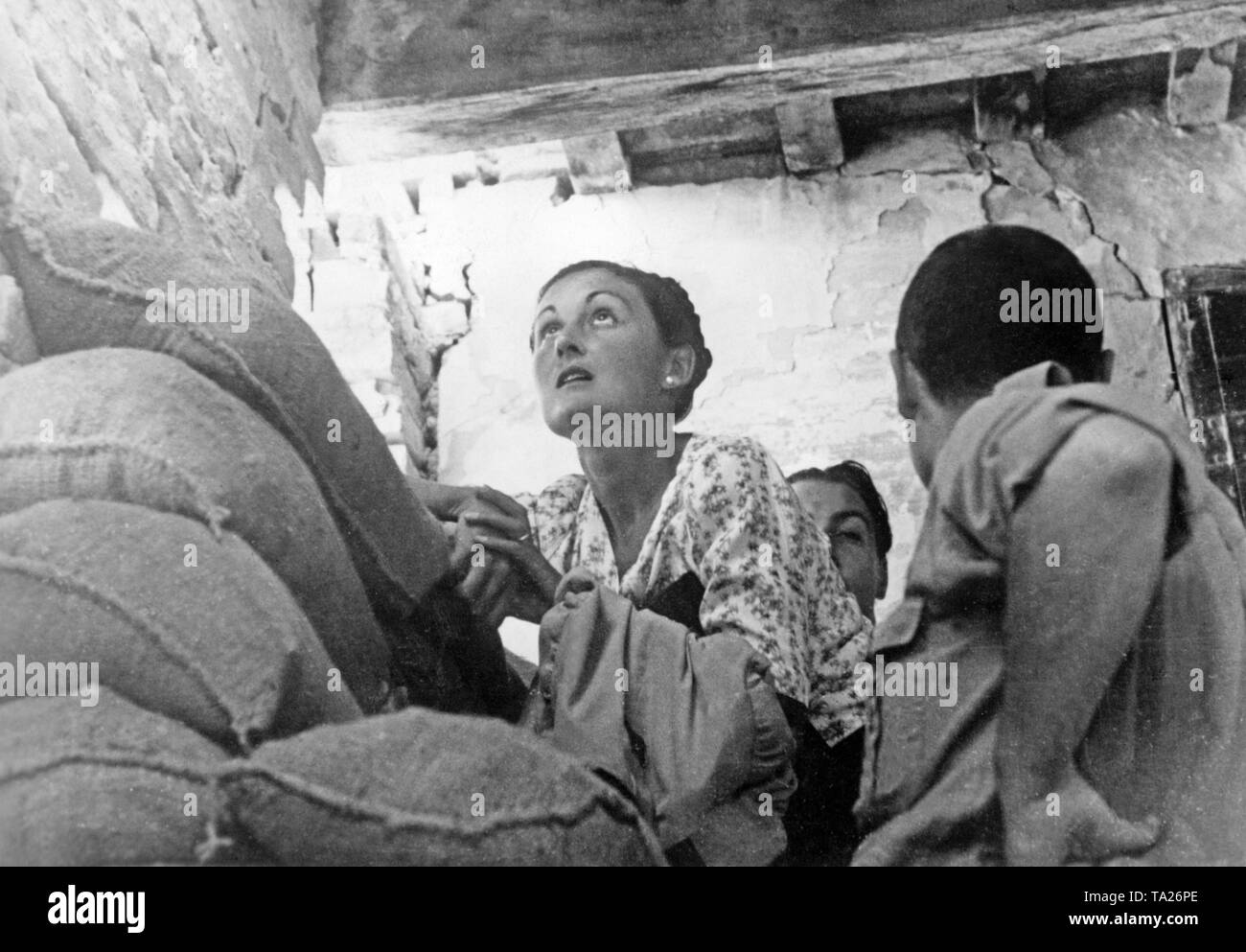 Photo of civilians, who are hiding from bomb attacks in a house behind sandbags during the siege of Madrid by Spanish national troops. Stock Photo