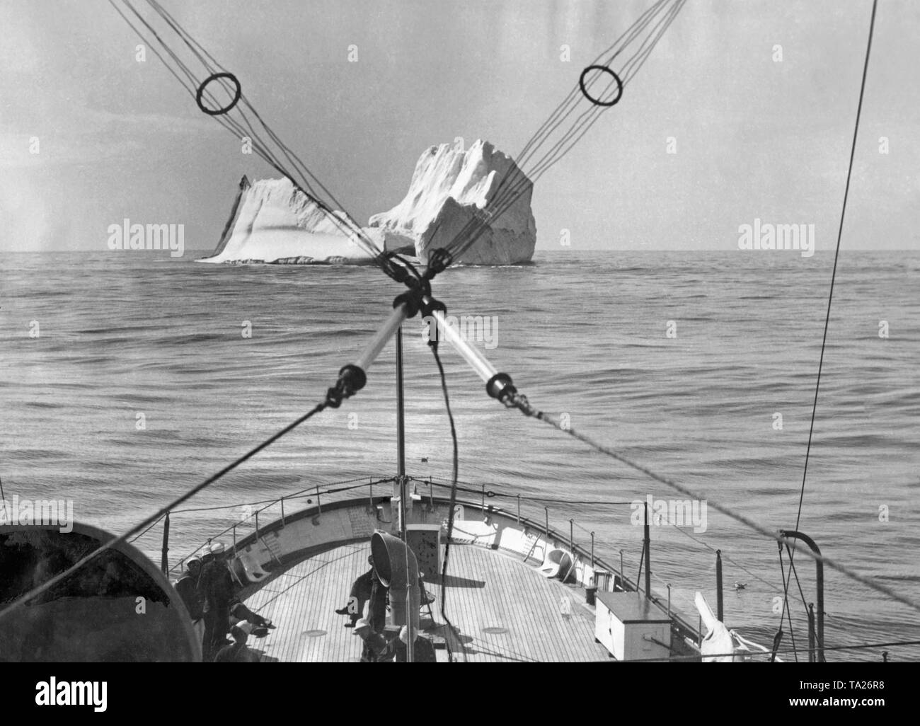 A ship of the International Ice Patrol is heading for an iceberg. In the 1920s, large icebergs were blown up to minimize the risks of transatlantic shipping. Stock Photo
