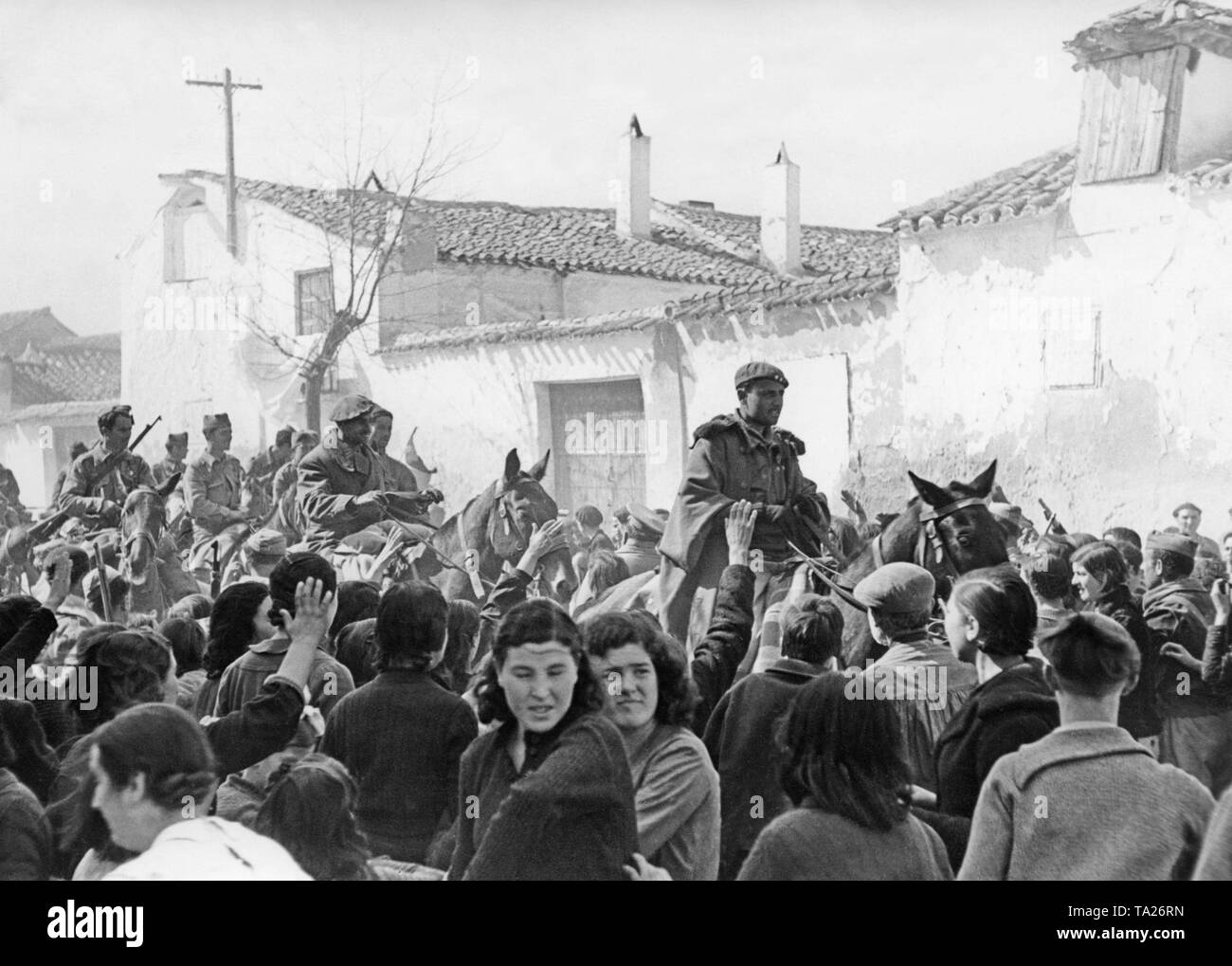 A Spanish national cavalry unit of the Moroccan Foreign Legion (Fuerzas Regulares Indigenas) in the village of Templique near Toledo on March 29, 1939. Armored units had been pulled through the village before. In the foreground, the inhabitants are giving the Fascist salute. Stock Photo