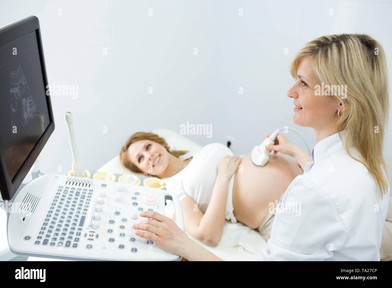 Happy woman looking at ultrasound results with her doctor in examination room Stock Photo