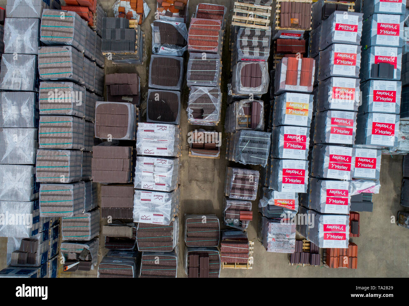 Pallets of bricks, tiles and other building materials in a builders merchant yard, shot with a drone Stock Photo
