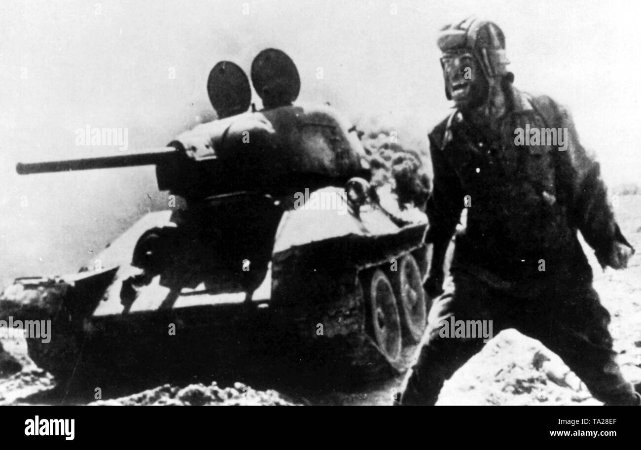 In this undeniably impressive Russian picture, taken during the Battle of Berlin, the commandant of a Russian tank has been able to make a last-minute exit from his tank which has been hit and set on fire. Wild with excitement, the commandant is yelling at his comrades, ordering them to continue their attack. Stock Photo