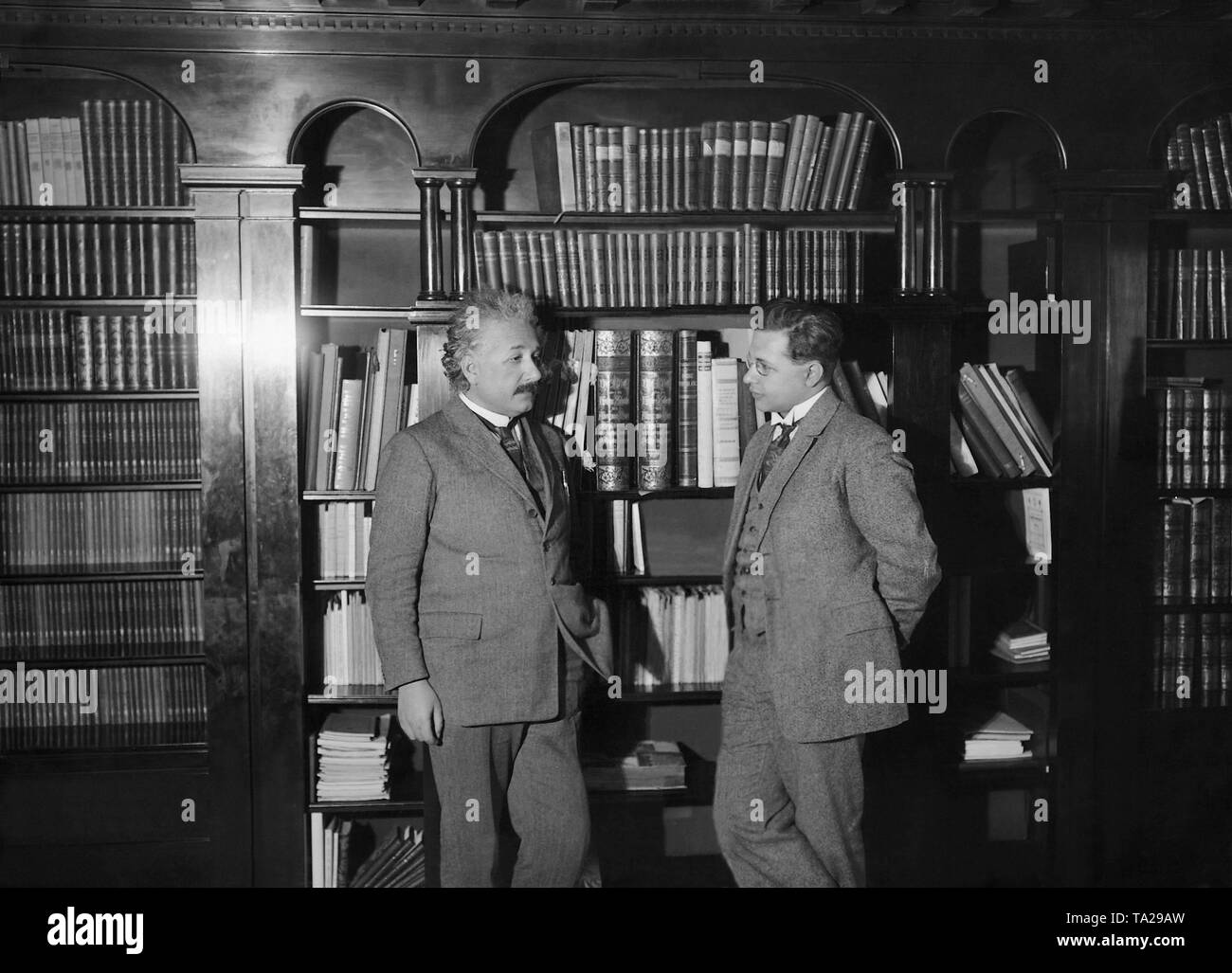 The physicist and Nobel Prize winner (1921) Albert Einstein stands in front of bookshelves with his son Albert. Undated photo, probably from the 1930s. Stock Photo