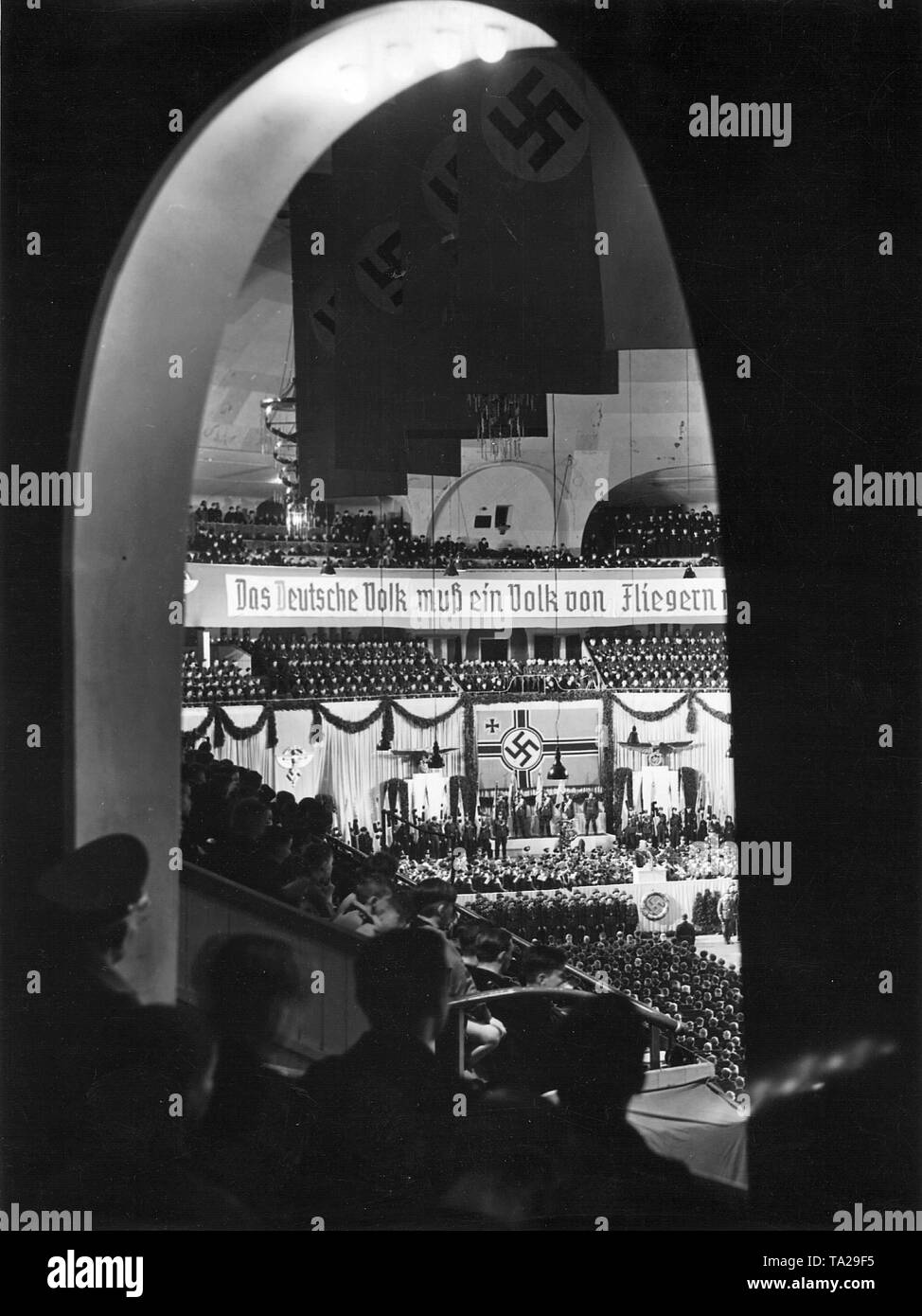 Mass rally of Air Force. Nazi Air Force Corps and Hitler Youth at the opening of the propaganda week of the Luftwaffe. Above the flag-bearer a flag of the Luftwaffe, above the banner reading "Das deutsche Volk muss ein Volk von Fliegern" (The German nation must become a nation of fliers). Stock Photo