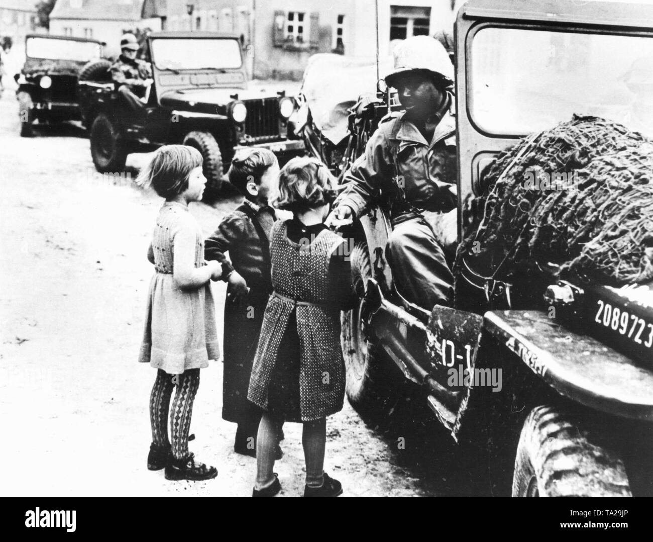 An African-American soldier presenting German children with chocolate or chewing gum. Stock Photo