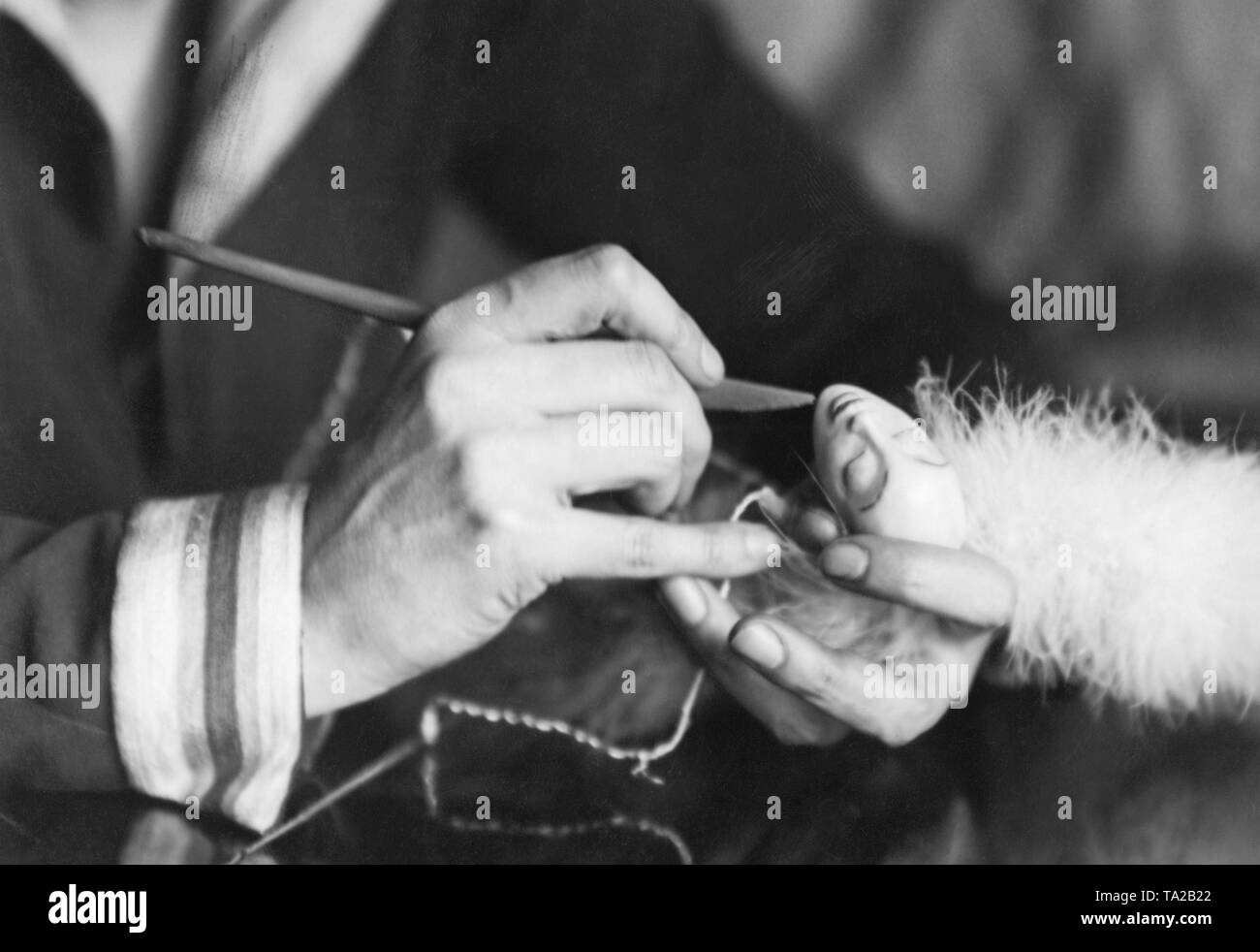 A woman models the head of a porcelain doll (undated image). Photo