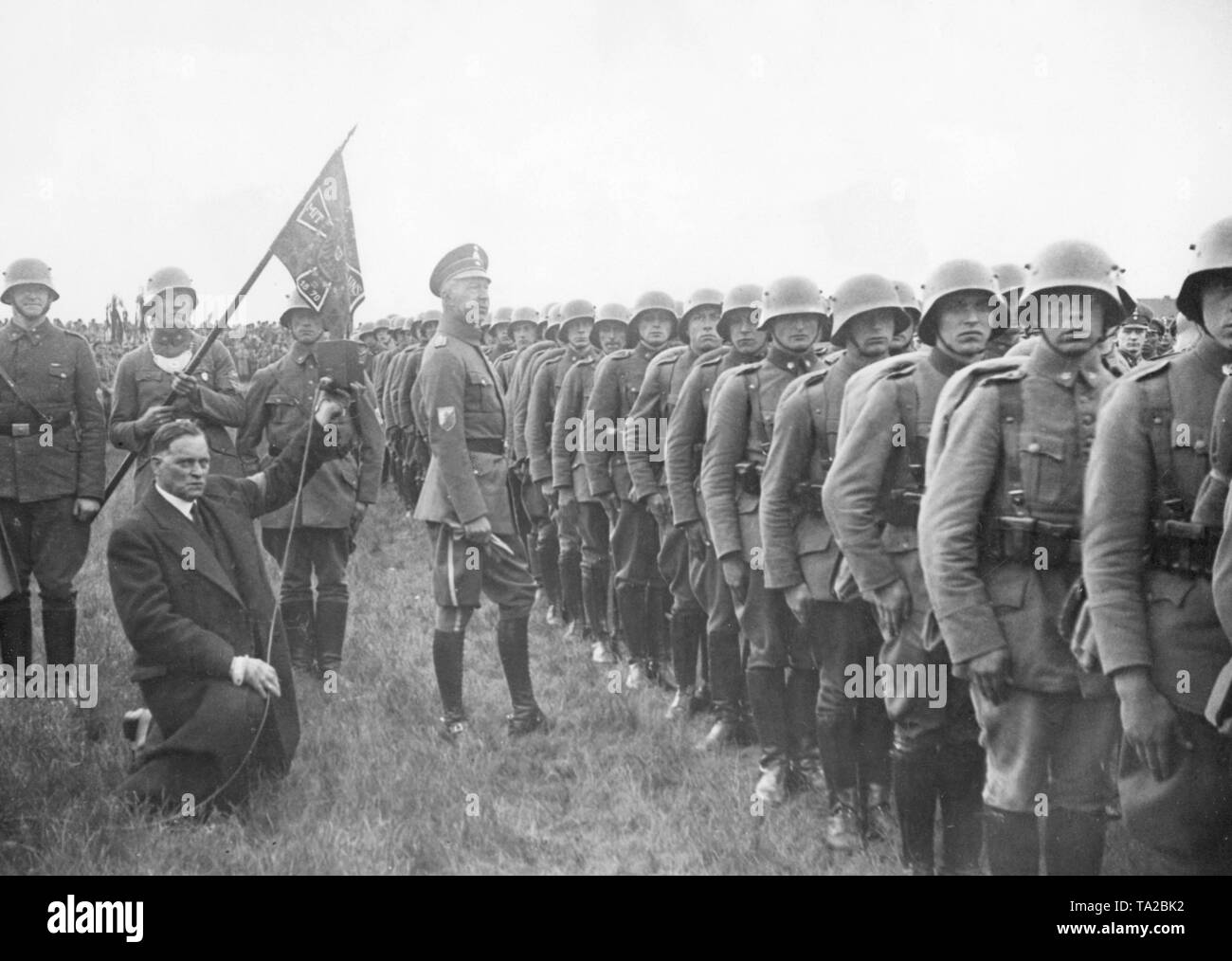 The Crown Prince Wilhelm of Prussia stands in front of the field standard, which was donated by him to the Jung Stahlhelm regiment 'Kronprinz von Preussen' . On the right is a company in field equipment. Stock Photo