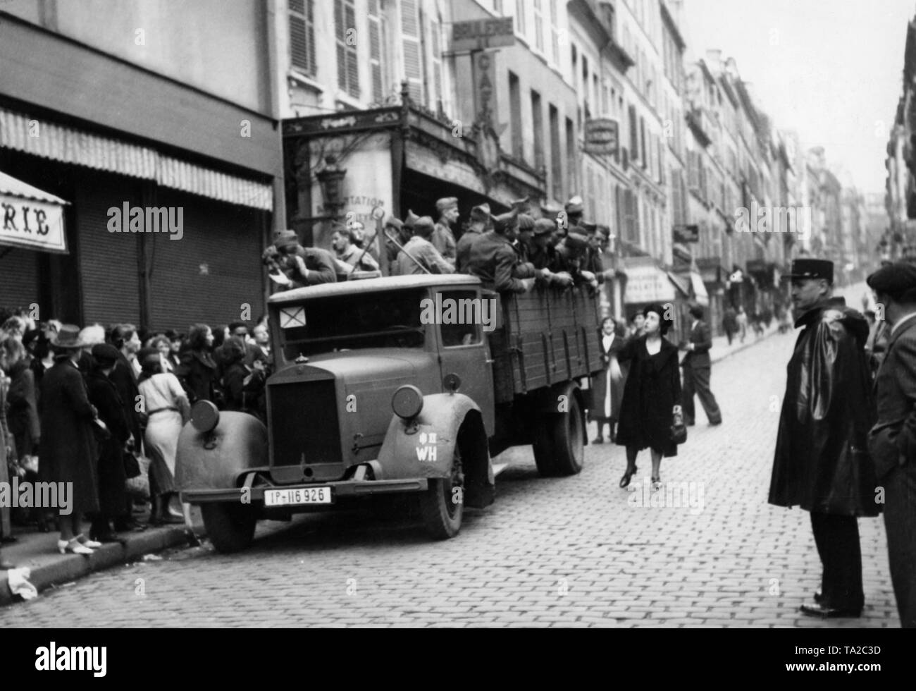 A truck with French soldiers in the Rue des Martyrs in Paris. The soldiers are driven in a German truck through Paris, which stops here, so that Parisians can supply their compatriots. Stock Photo
