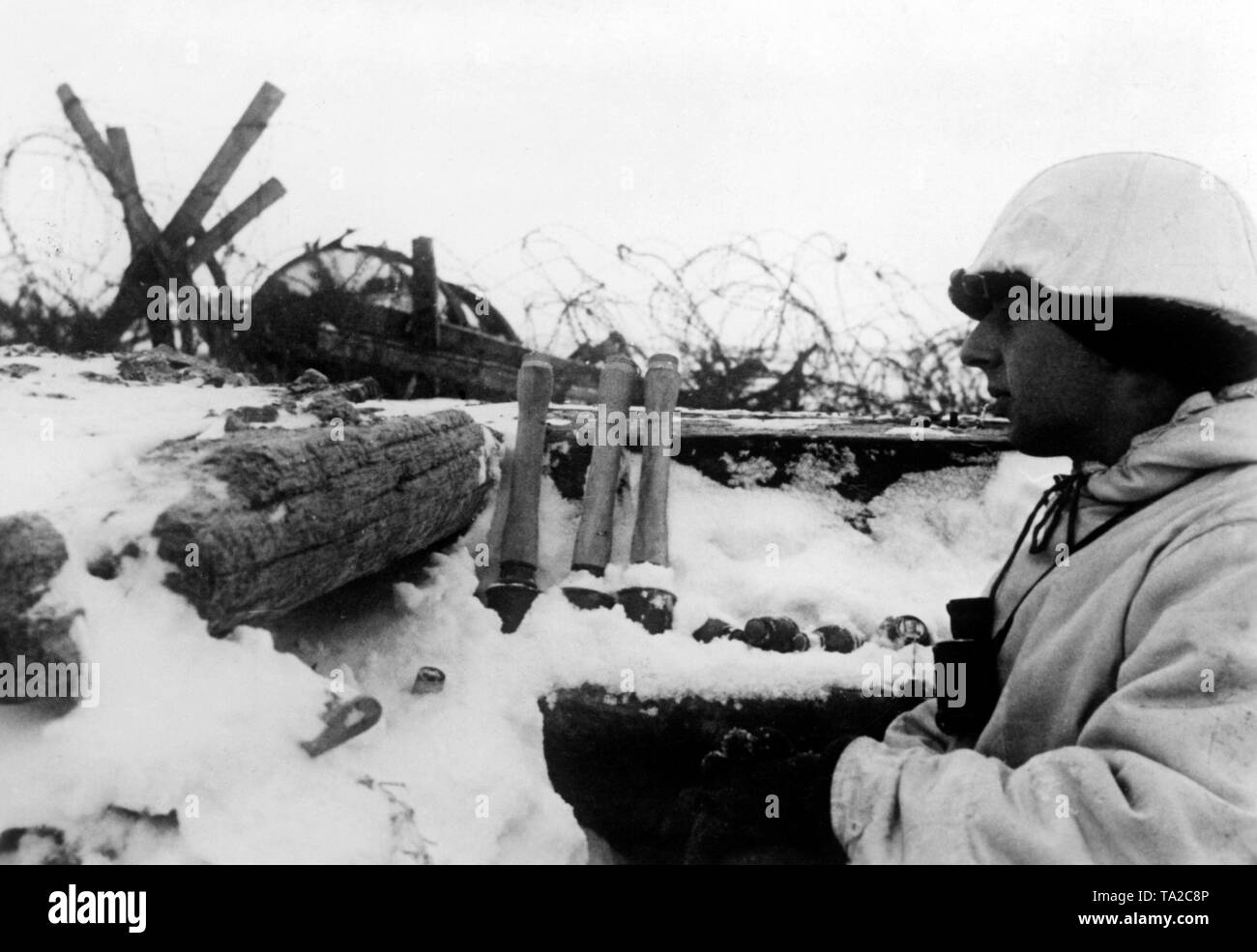 A German soldier observes the surroundings out of a ditch. Next to him, hand grenades. The ditch is located directly on the tracks of the tram line in Leningrad. Photo of the Propaganda Company (PK): war correspondent Freckmann. Stock Photo