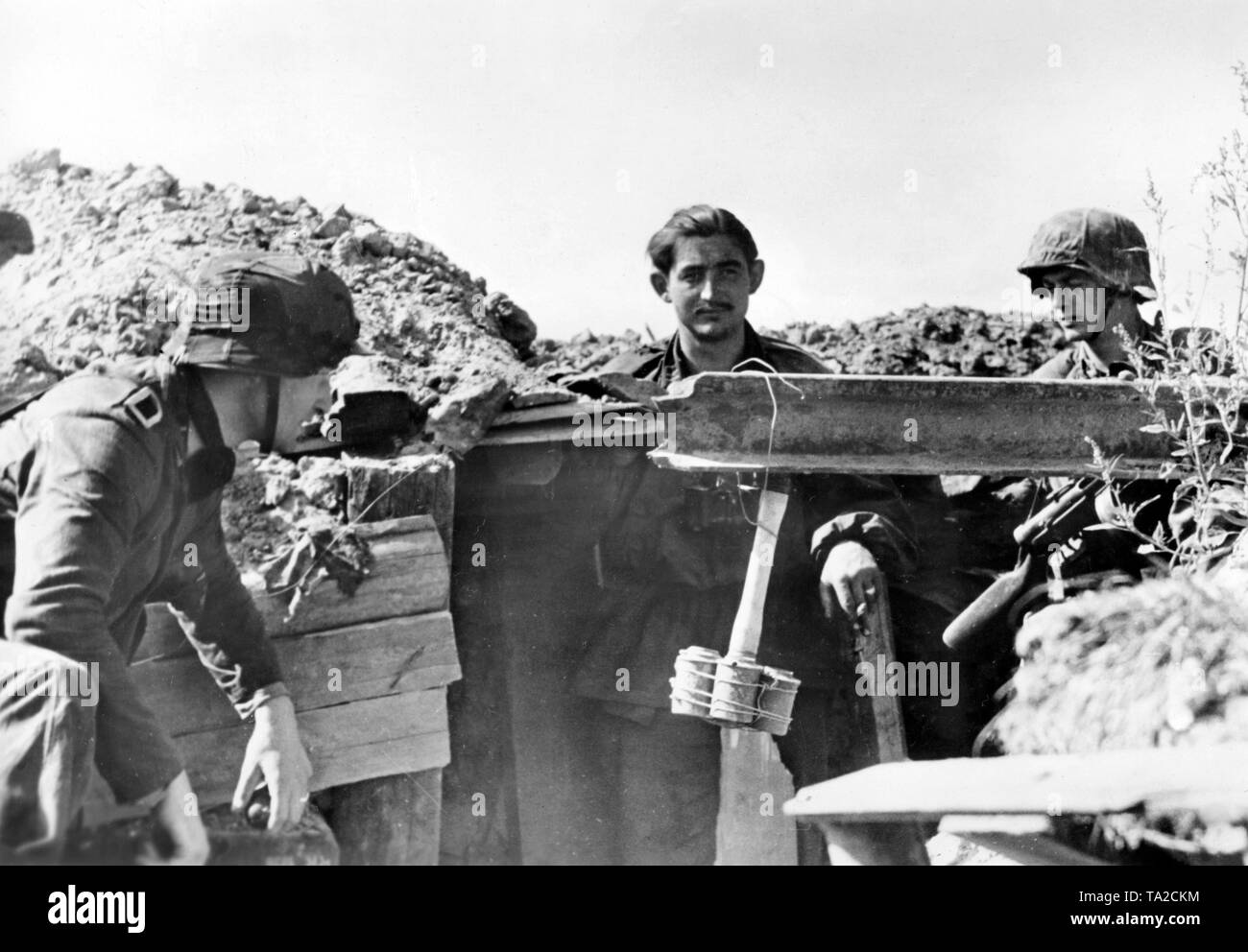 German soldiers during a pause in the fighting in a ditch at Leningrad. A demolition bomb hangs ready to be used. Photo of the Propaganda Company (PK): SS war correspondent Hilkenbach. Stock Photo