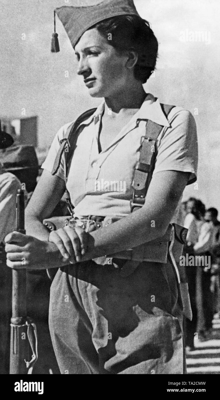 Close shot of a Republican militiaman during training in Madrid shortly after the outbreak of the Spanish Civil War in June in August, 1936. The woman is wearing a polo shirt, breeches, a belt and a gorillo cap. She leans on a carabiner. In the background, other volunteer militiamen. Stock Photo