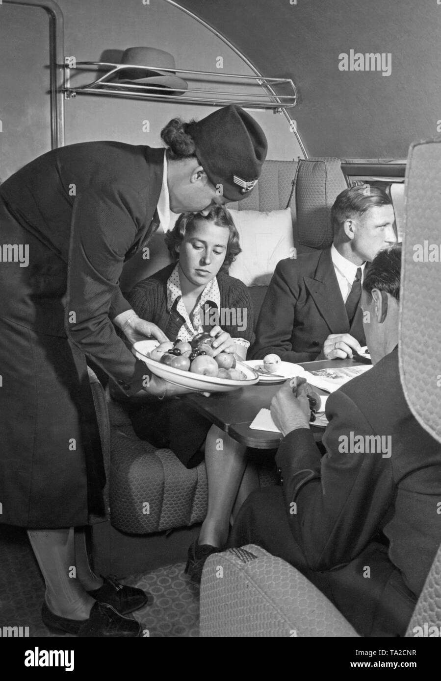 A Lufthansa stewardess serves a first-class passenger. Stock Photo