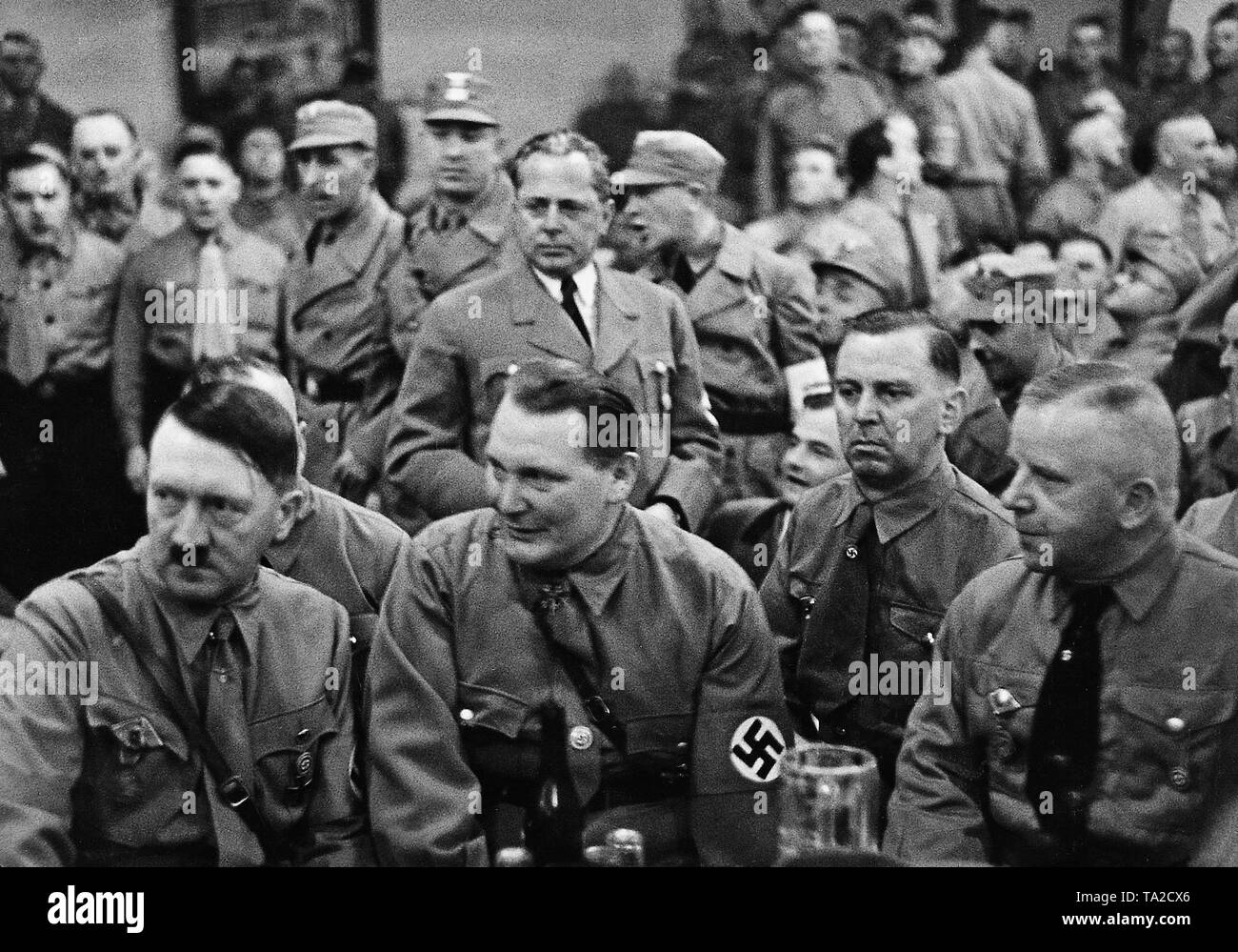 Adolf Hitler during the traditional meeting in the Munich Buergerbraeukeller to commemorate the 1923 coup attempt. Sitting from left: Adolf Hitler, Hermann Goering, Julius Schaub, Max Amann. Behind Goering, the photographer Heinrich Hoffmann. Stock Photo