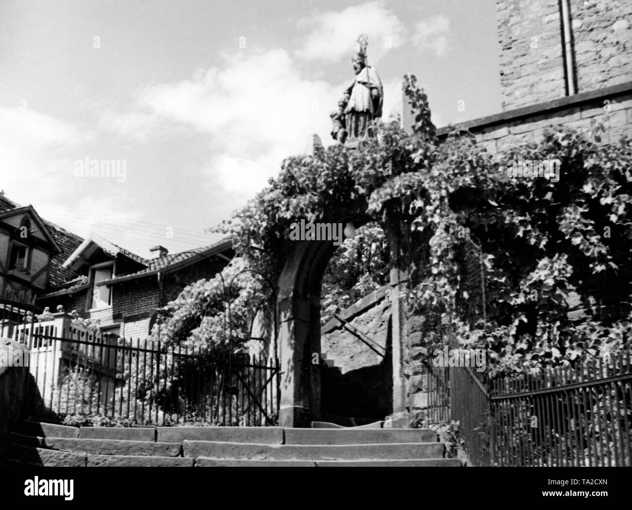 The staircase with vineclad archway is crowned by a statue of the