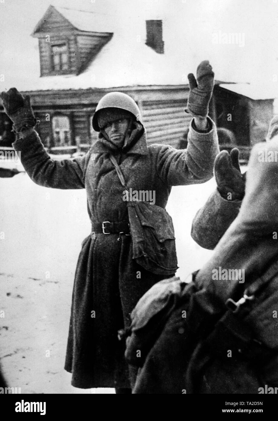 Russian prisoners of war stand with raised arms in front of German soldiers. Probably the picture was taken in a small city west of Moscow, during the retreat of the Wehrmacht. (PK photo: war correspondent Bauer). Stock Photo