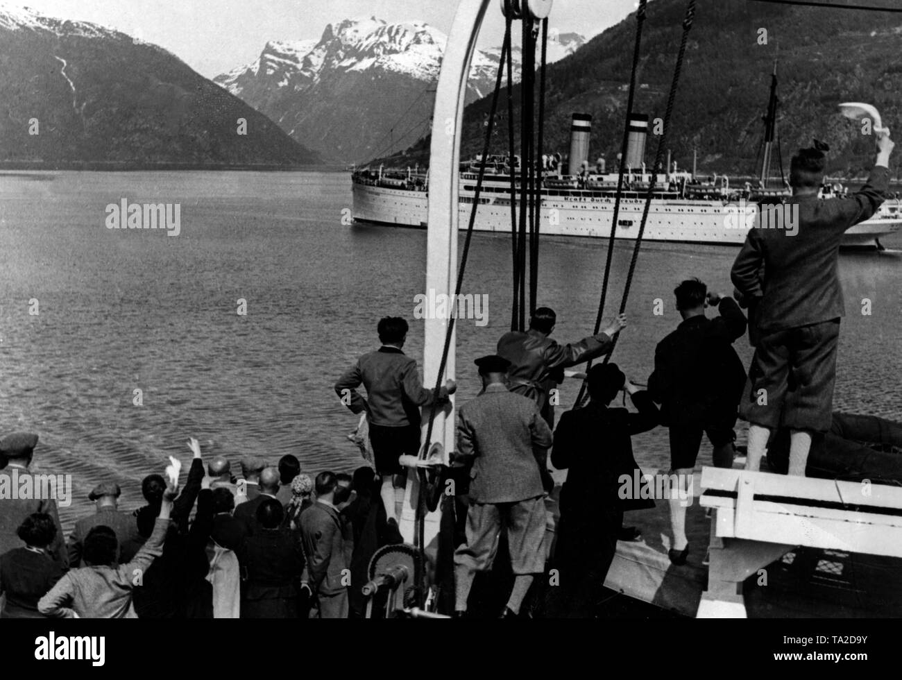 Undated photo of vacationers of the Nazi organization 'Kraft durch Freude' ('Strength through Joy') on a KdF ship, who welcome another KdF ship in a fjord on the Norwegian coast. In the background snow-covered mountains. Stock Photo