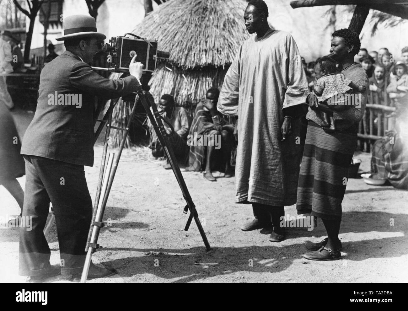 A camera-man films displayed colored people for a film documentary of the 'Wochenschau'. People of different ethnicities were introduced at the ethnological exposition. One of the most well-known ethnological exposition host was Carl Hagenbeck. Women were announced as 'Lippennegerinnen'. Stock Photo