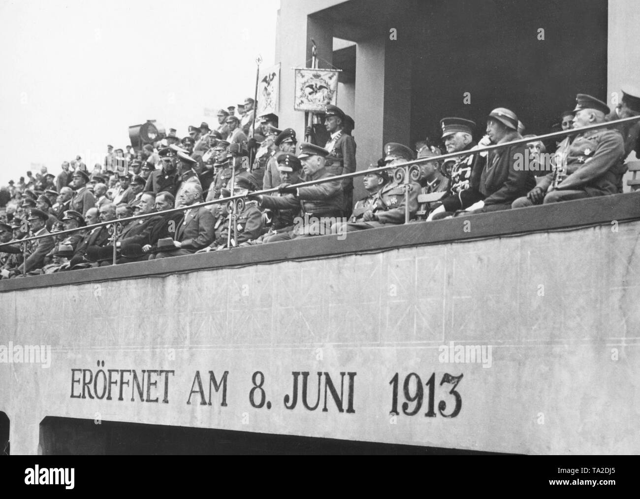In the VIP box sit prominent figures, including the leaders of the Stahlhelm Theodor Duesterberg (in the middle, hands on the parapet) and Franz Seldte (left beside him), and on the left the representatives of the Reich government, such as the Reich Interior Minister (with cigarette, glasses and hat in the lap). On the right, Generalfeldmarschall August von Mackensen (black uniform). On the grandstand the inscription: 'Opened on June 8, 1913'. Stock Photo