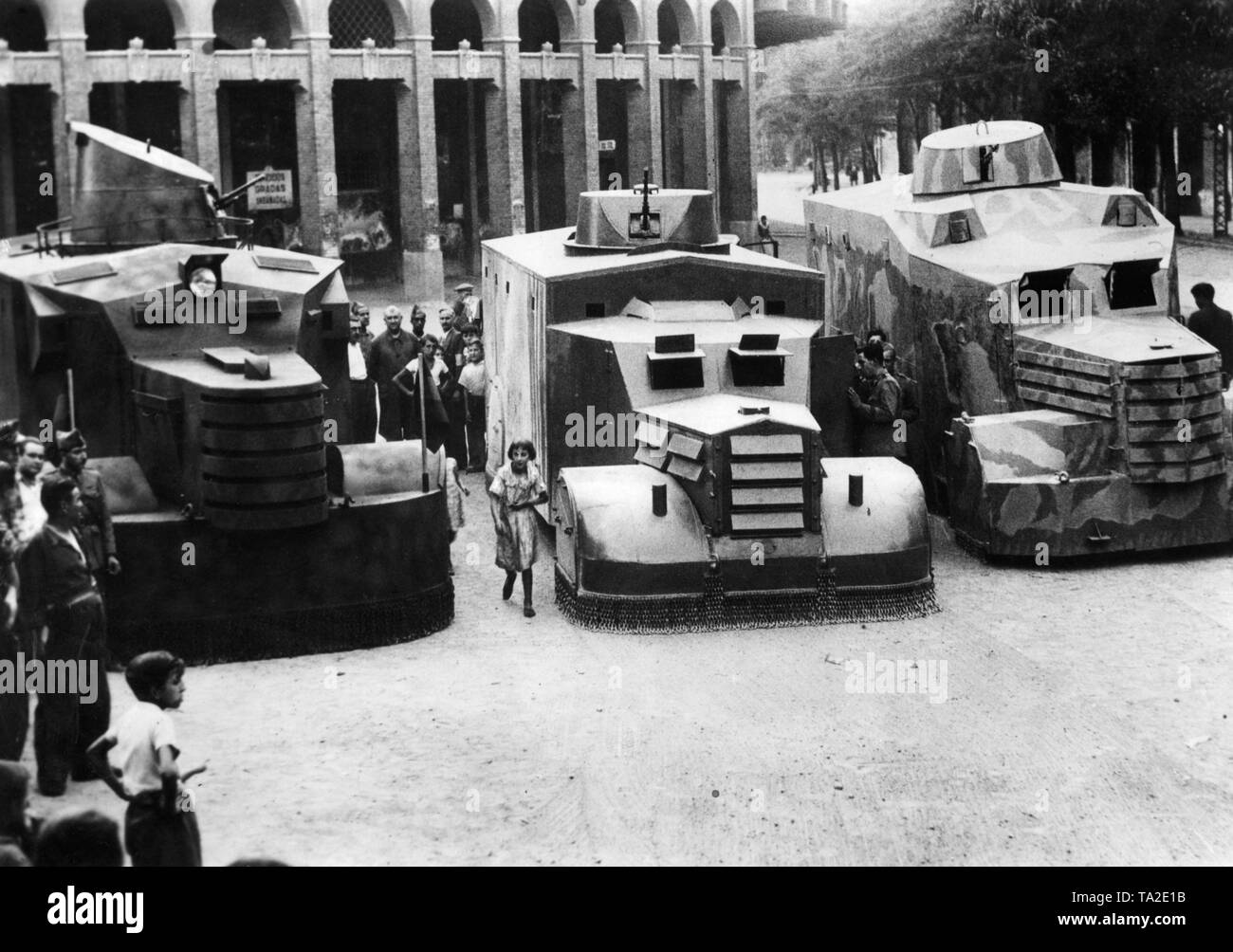 Photo of three Republican armored cars on the Calle de Ramon Pignatelli in front of the bullring in Zaragoza, Aragon, after the outbreak of the Spanish Civil War in 1936. Such armored vehicles used by the Republican troops consisted mostly only of trucks reinforced with armor plates, which were armed with a turret machine gun. The vehicles had little military value due to their size, low armament and  lack of mobility. Therefore they were used primarily for troop transport. The vehicles are being watched by passers-by. Stock Photo