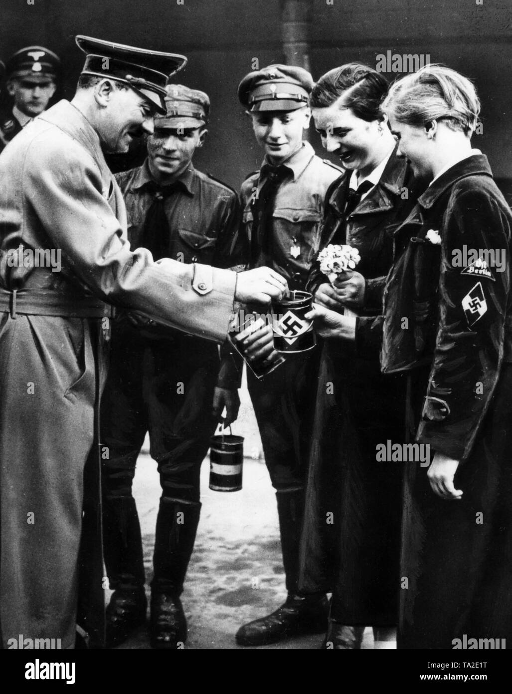 Adolf Hitler (left) buys flowers from HJ and BDM members, who are collecting money for youth hostels. The picture was made in the summer of 1936 before the Reichskanzlei. Stock Photo