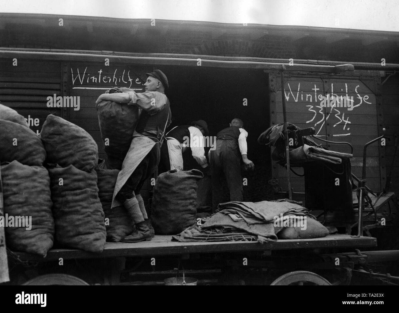 Workers unload potato bags from a train which the Winterhilfe had received as donation. Stock Photo