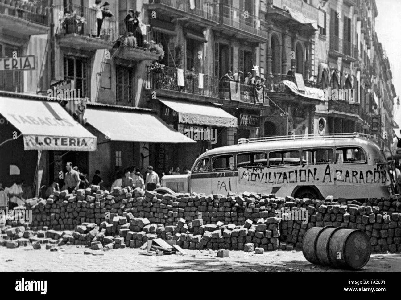 The picture shows a Republican barricade built of stones and a bus in the center of Barcelona in the summer of 1936, shortly after the outbreak of the civil war. On the wagon are the abbreviations FAI (Federacia Anarquista Iberica) and CNT (Confederacion Nacional del Trabajo). Stock Photo