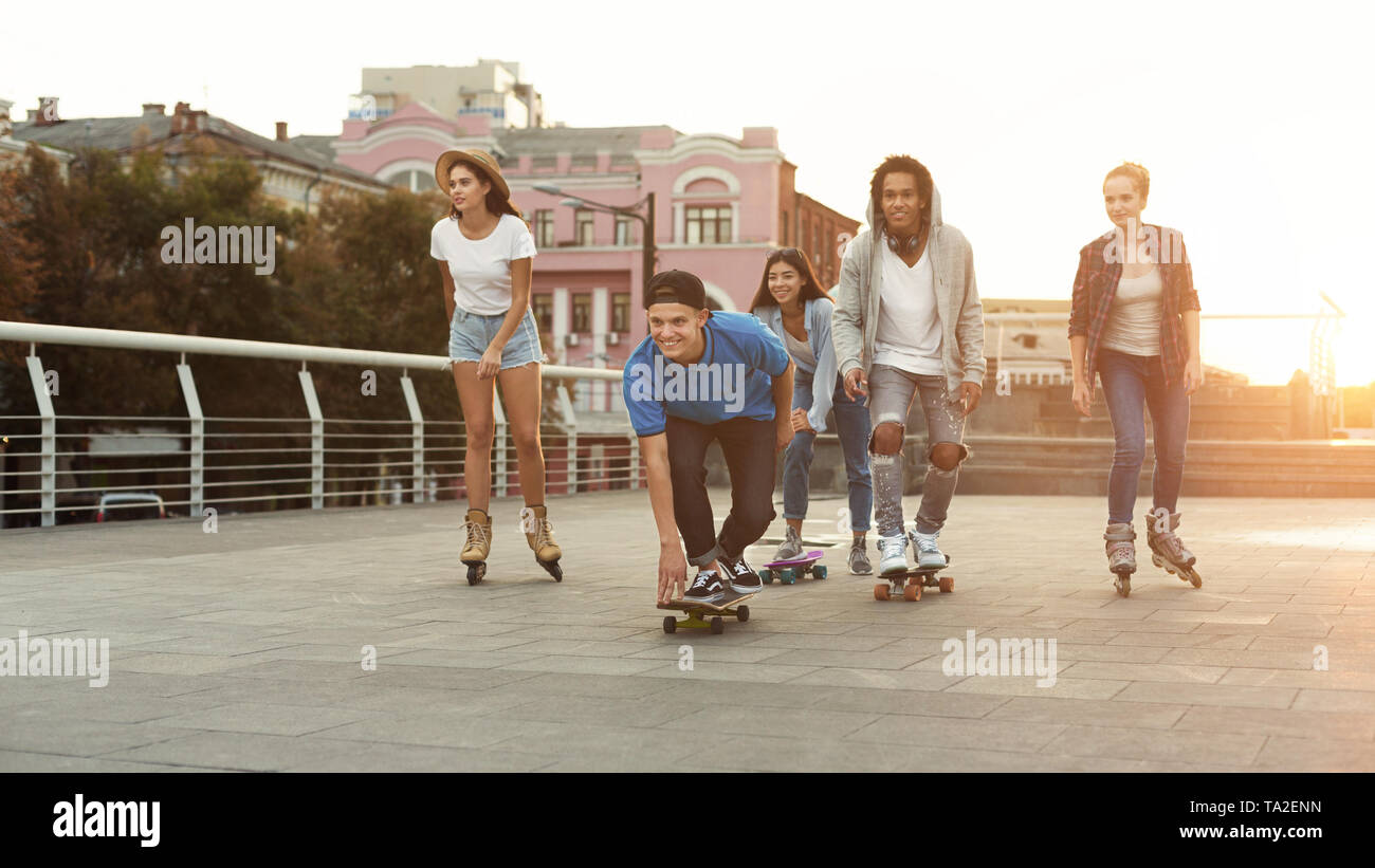 Diverse Teen Friends Riding on Skateboards and Rollers Stock Photo