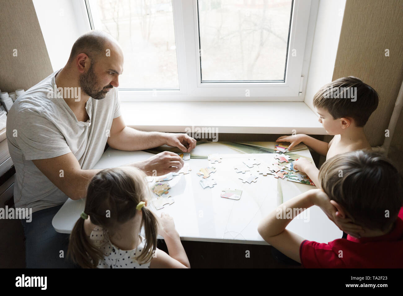Family leisure: father, sons and daughter play board games together Stock Photo