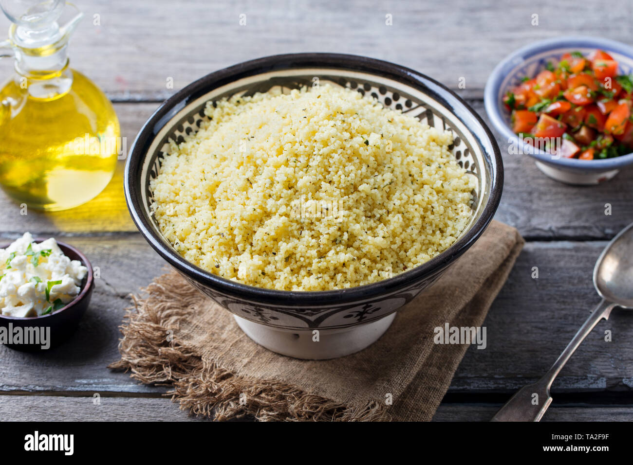 Couscous in bowl with olive oil. Wooden background. Close up. Stock Photo