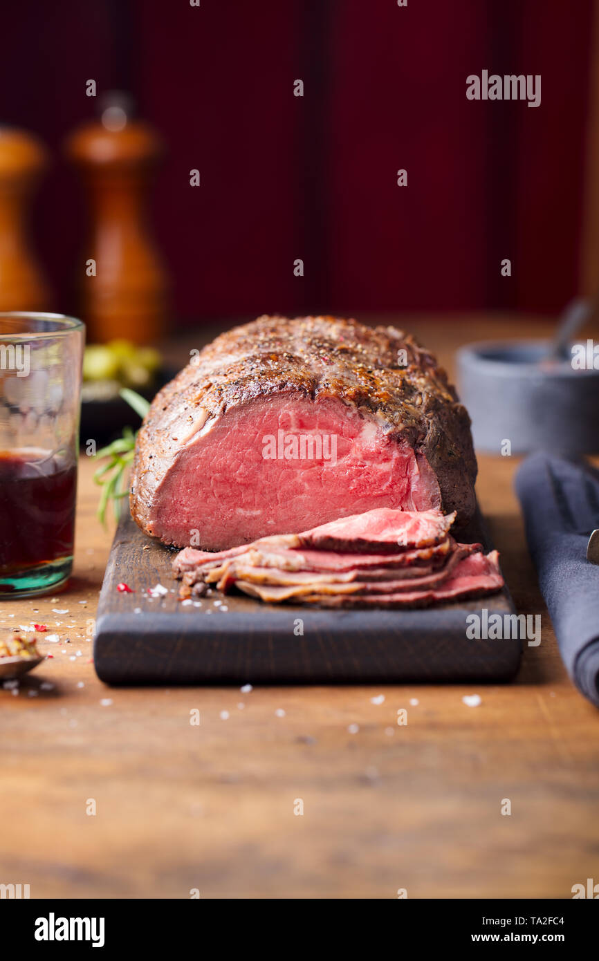 Roast beef on cutting board. Wooden background. Copy space. Stock Photo