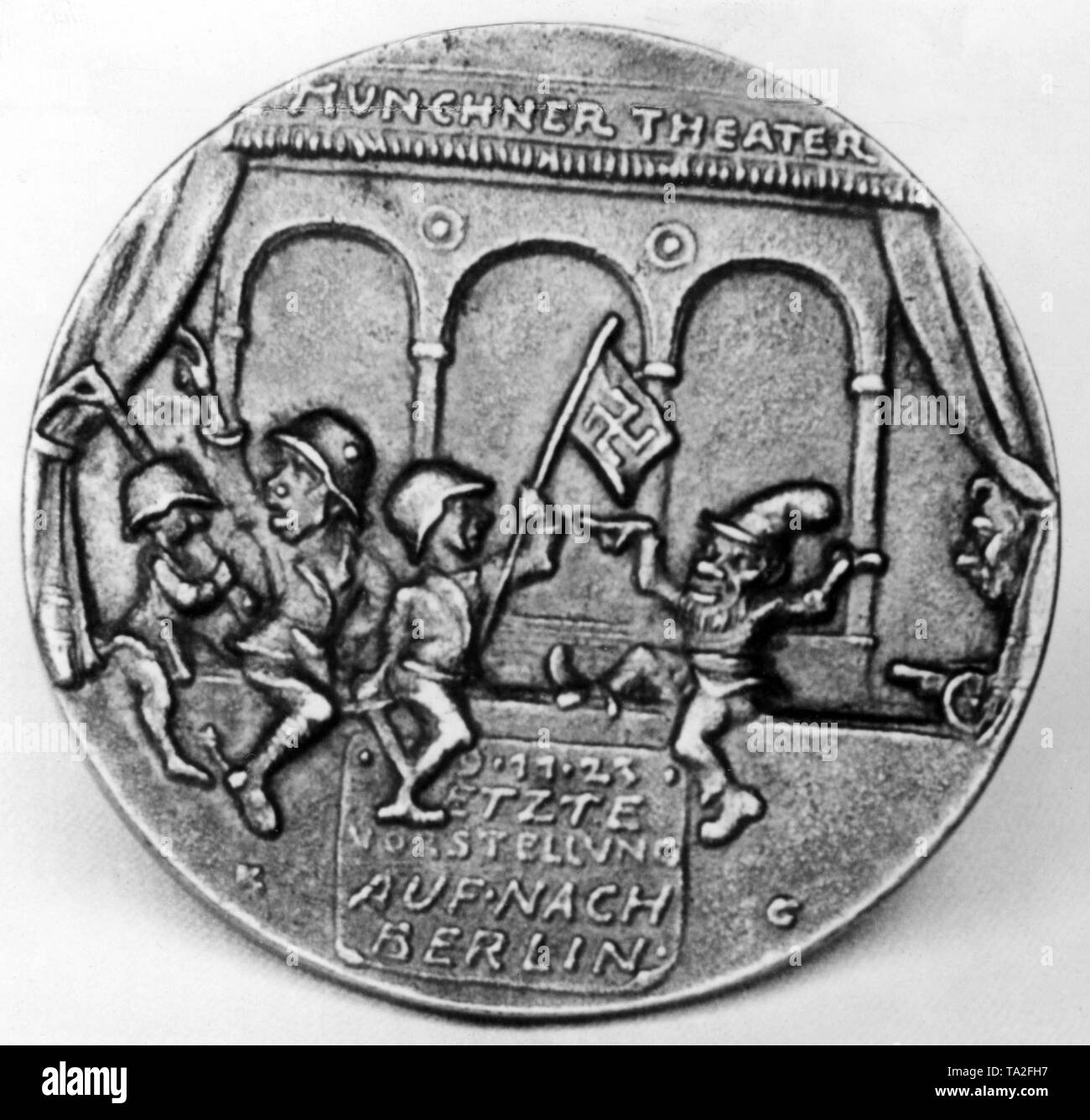 Back of a medal on the Beer Hall Putsch by Karl Goetz. The Beer Hall Putsch is depicted as the 'Munich Theater'. It shows Adolf Hitler (in the middle, with steel helmet) and two putschists with gallows and a swastika flag. On the right a Kasperl is dancing. Below the figures is the inscription: '9.11.23 Last performance, let's go to Berlin'. Stock Photo