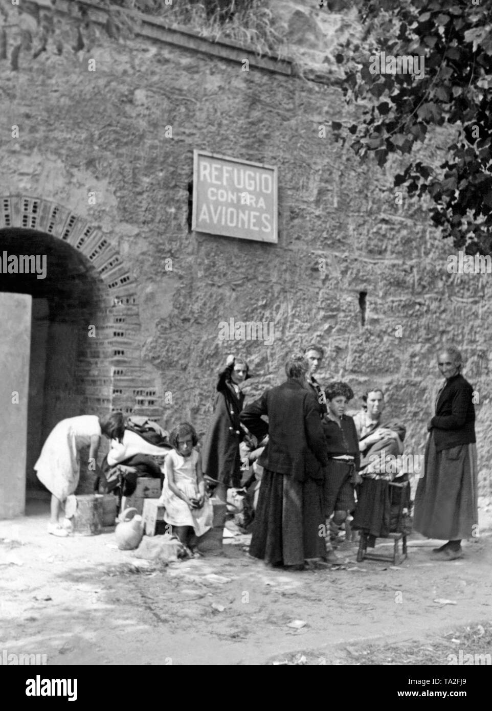 Spanish civilians return from an improvised air-raid shelter after a bomb attack (sign: Refugio contra aviones). The children of the family look frightened and intimidated. Stock Photo