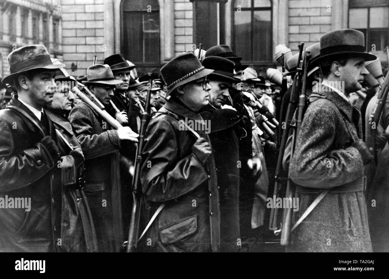Members of the German Volkssturm march through a German city. The men in the foreground carry Schmeisser MP-41 with wooden shaft, the man on the far right a Gebirgsjaegerkarabiner g33-40. The other members are armed with anti-tank rocket launchers. Stock Photo