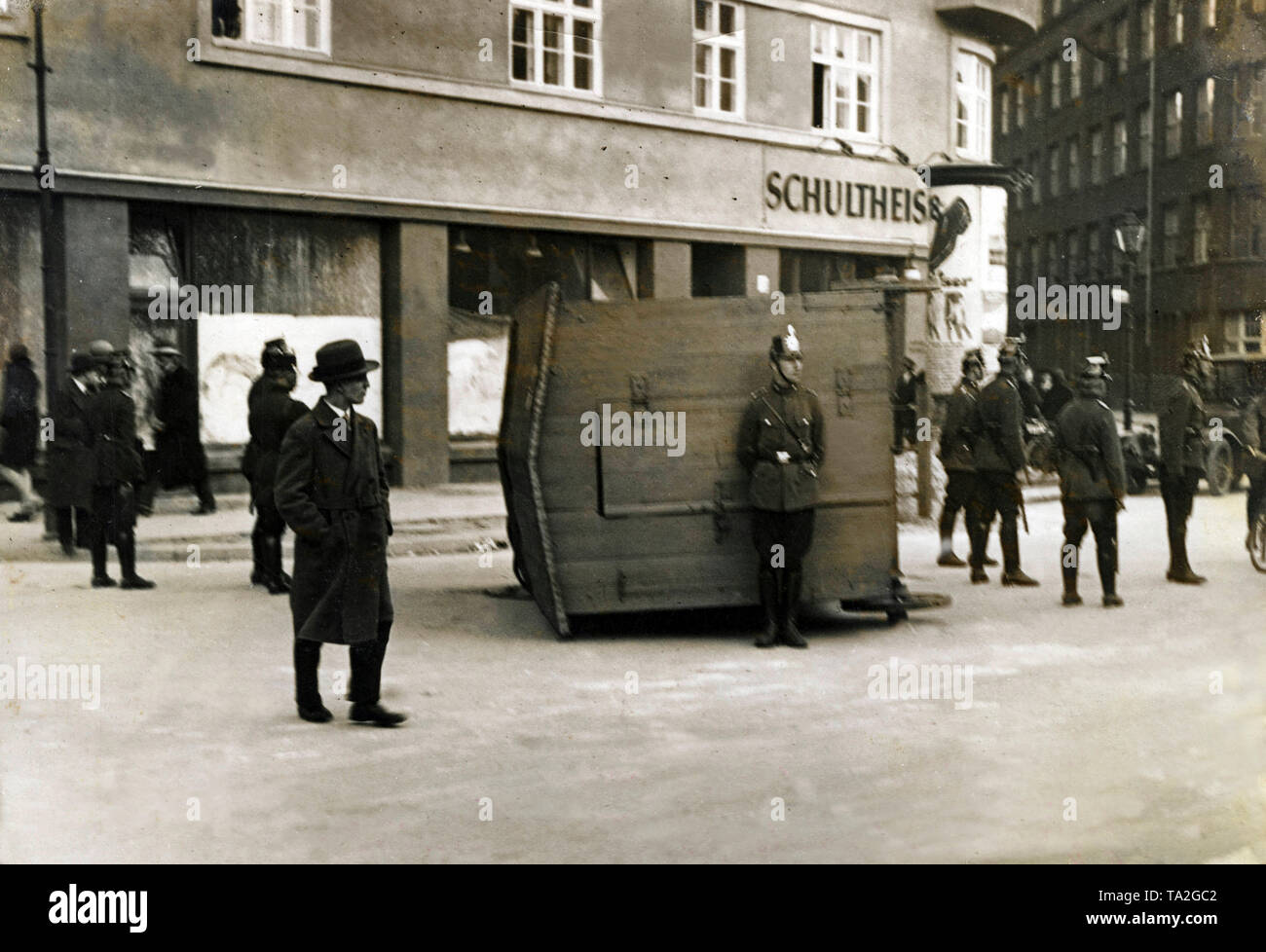 Policemen are looking for cover behind a crashed car.  When the Communist Party organized a mass demonstration on May Day  in Berlin, police opened fire on the participants. It came to a bloody street fight, which demanded numerous victims. Stock Photo