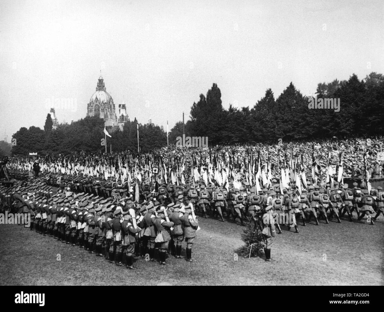At the leaders' meeting of the Stahlhelm in Hanover, the delegations are marching past the Stabchef (Chief of Staff) of the SA, Ernst Rohm (right). In the background, the New Town Hall of Hanover. On the left, a music band. Stock Photo
