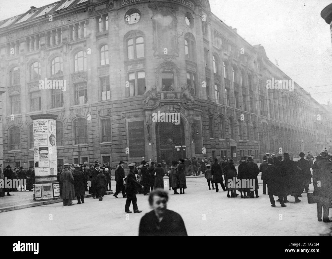 The Mossehaus at the corner of Jerusalemerstrasse / Schuetzenstrasse after its occupation by revolutionary troops. In front of the building passers-by watch the events. During the January uprising, there were armed conflicts in the Berlin Zeitungsviertel (newspaper quarter) between left-wing revolutionaries and government-loyal Freikorps units. Stock Photo