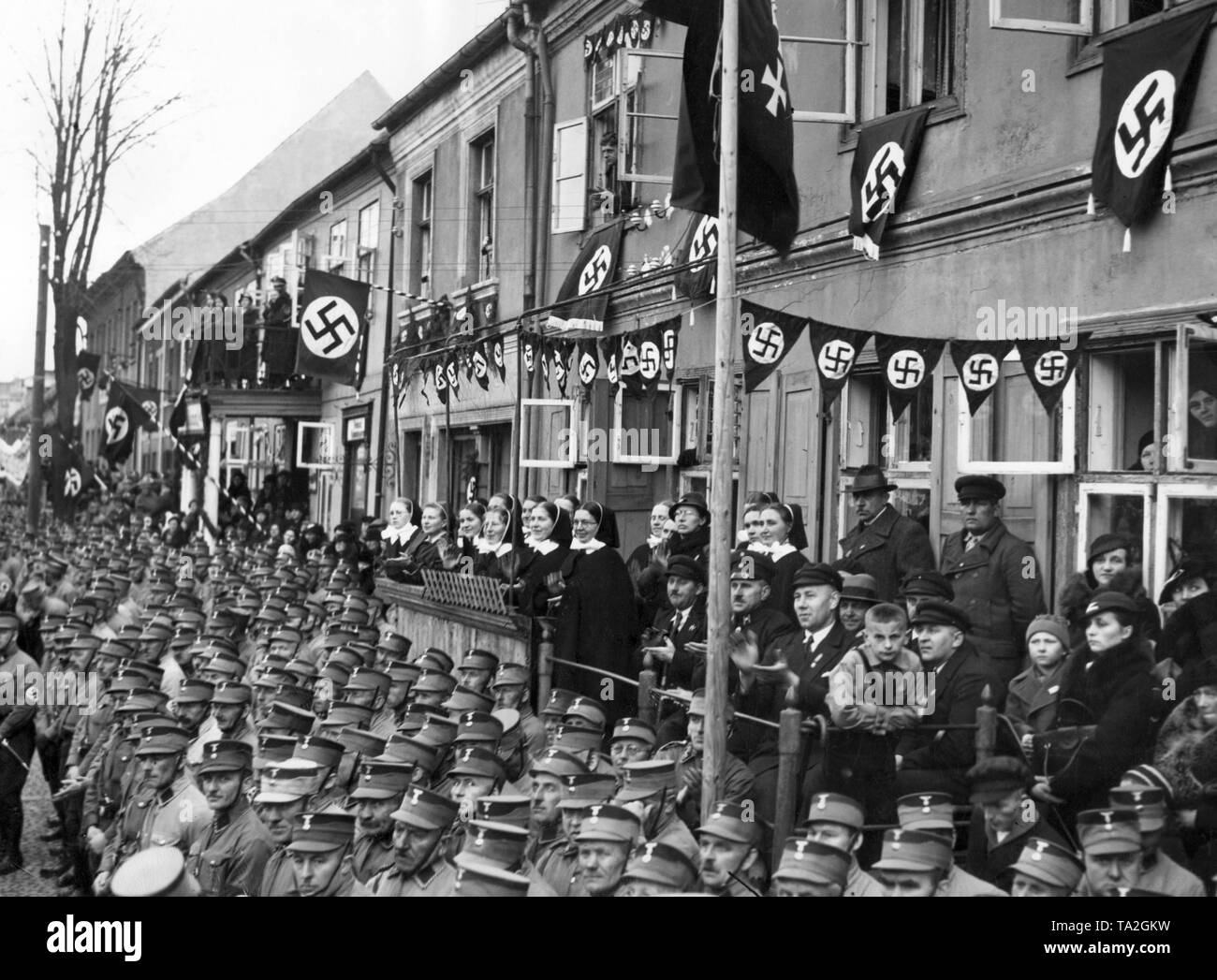 Photo of a crowd waiting for Reich Minister of Propaganda Joseph Goebbels,  who holds a propaganda speech at the Heumarkt on the occasion of the Volkstag elections. There are members of the SS and SS Heimwehr Gdansk, as well as nuns among the waiting people. Stock Photo