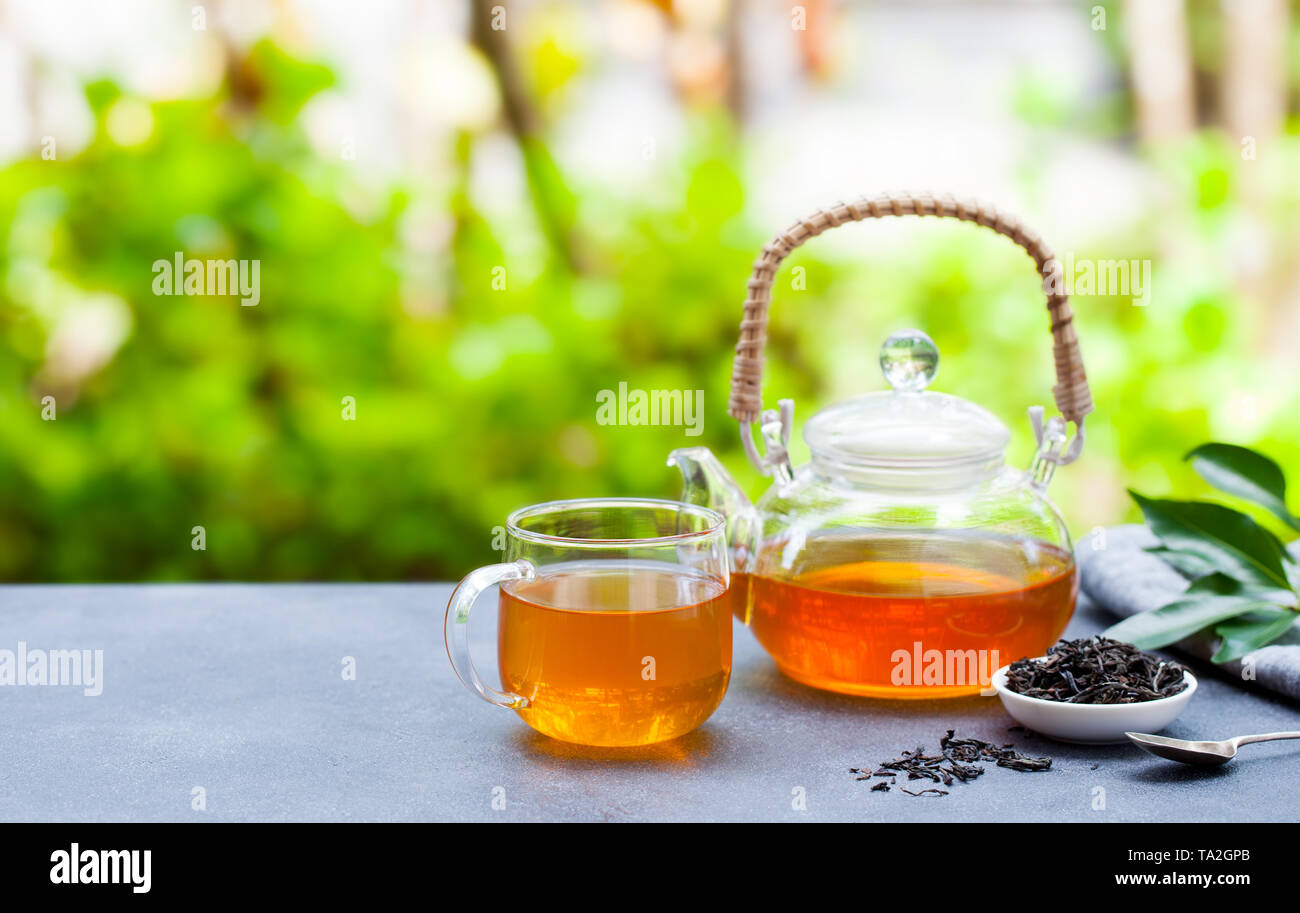 Tea in glass cup and teapot on summer outdoor background. Copy space. Stock Photo