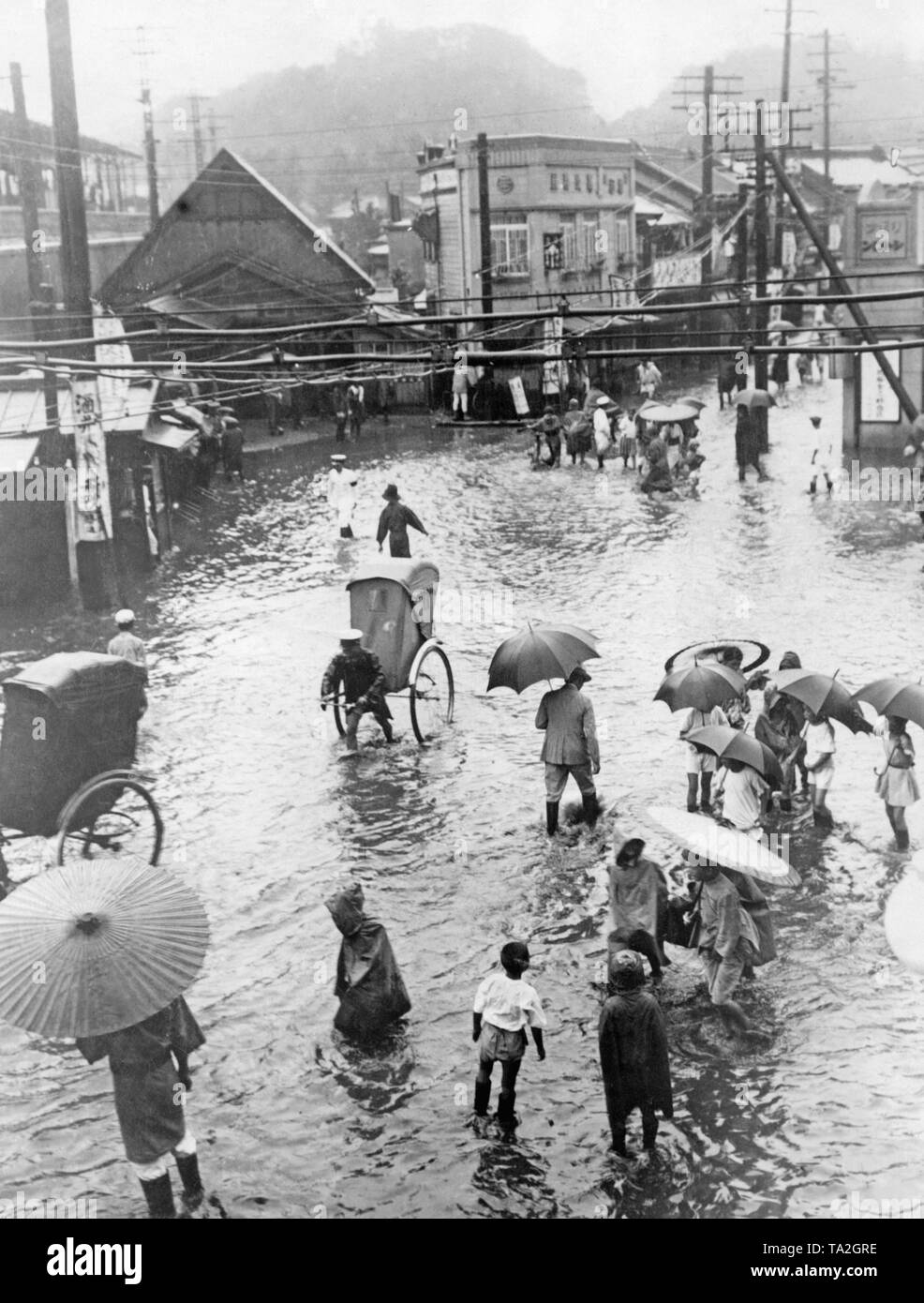 After a storm in Japan, a street in Tokyo is under water. Many people wade through the water. Stock Photo