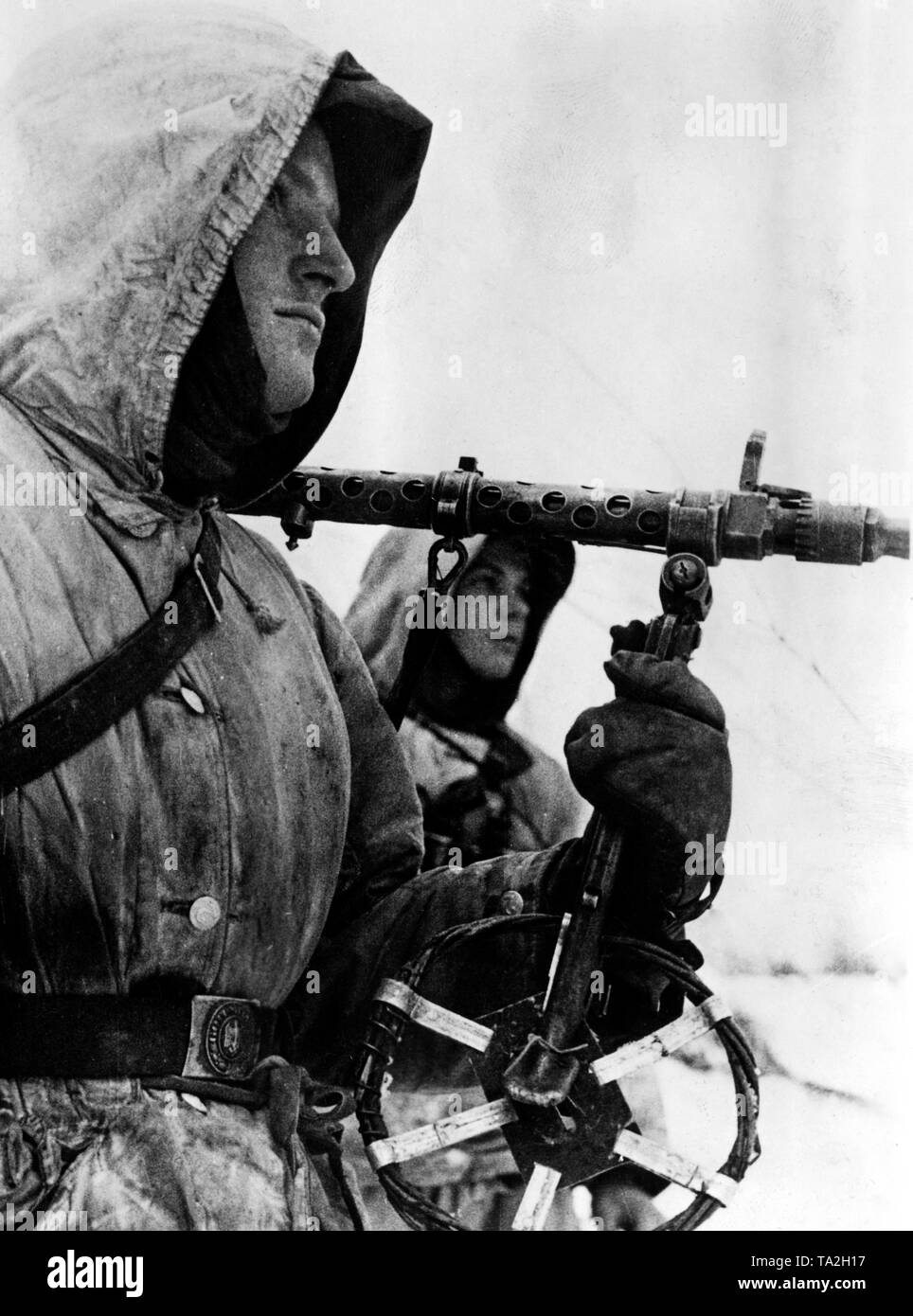 German soldiers during winter fighting near the city of Toropez at the northern section of the Eastern Front. A soldier carries a Maschinengewehr 34 on his shoulder, in his hand he holds a bipod, which is to prevent the sinking of the machine gun into the snow. Photo of the Propaganda Company (PK): war correspondent Hermann. Stock Photo