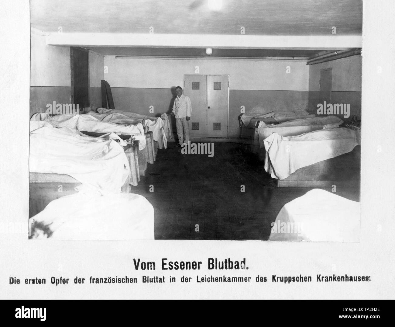 After the French occupation soldiers had shot several Krupp employees, the corpses of the so-called blood sacrifice were laid out covered with cloths in the morgue on the site of the Krupp company. Stock Photo