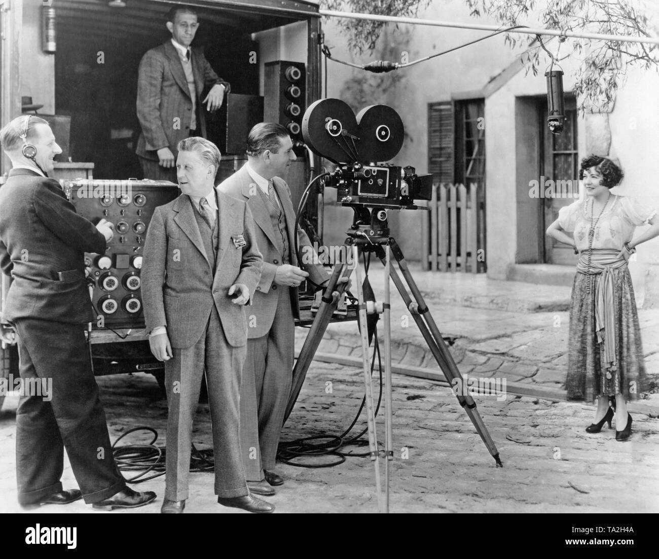 Photo of director Fred Niblo (on the left next to the cameraman), next to him, cameraman John Arnold and actress Renee Adoree. A sound engineer turns the controller of the new portable sound recorder. Metro Goldwyn-Meyer was the production company of the film. Stock Photo