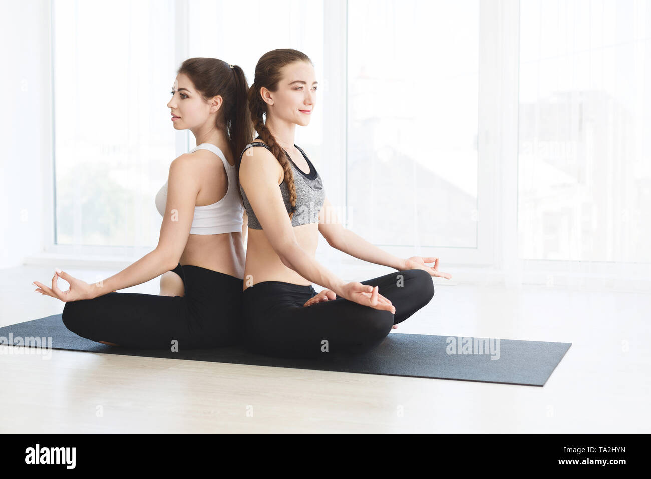 Two attractive women in sportswear on white background doing yoga Stock Photo