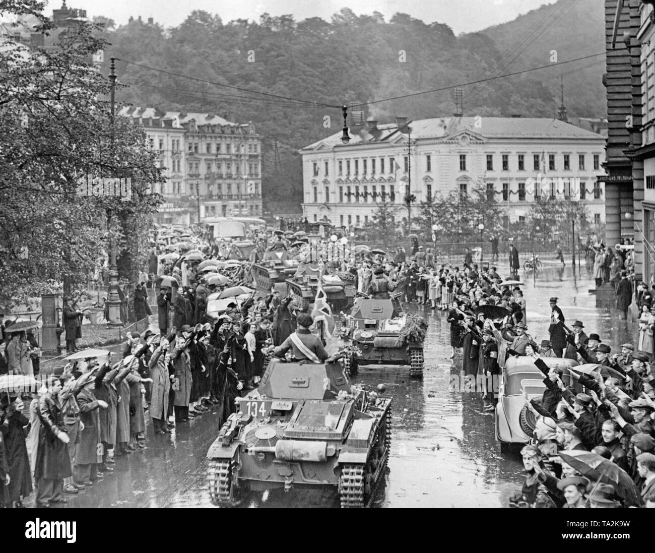 An armored regiment of the Wehrmacht drives into Karlsbad (today Karlovy Vary) with its Panzer I on October 4, 1938. The soldiers are welcomed by cheering people. Stock Photo