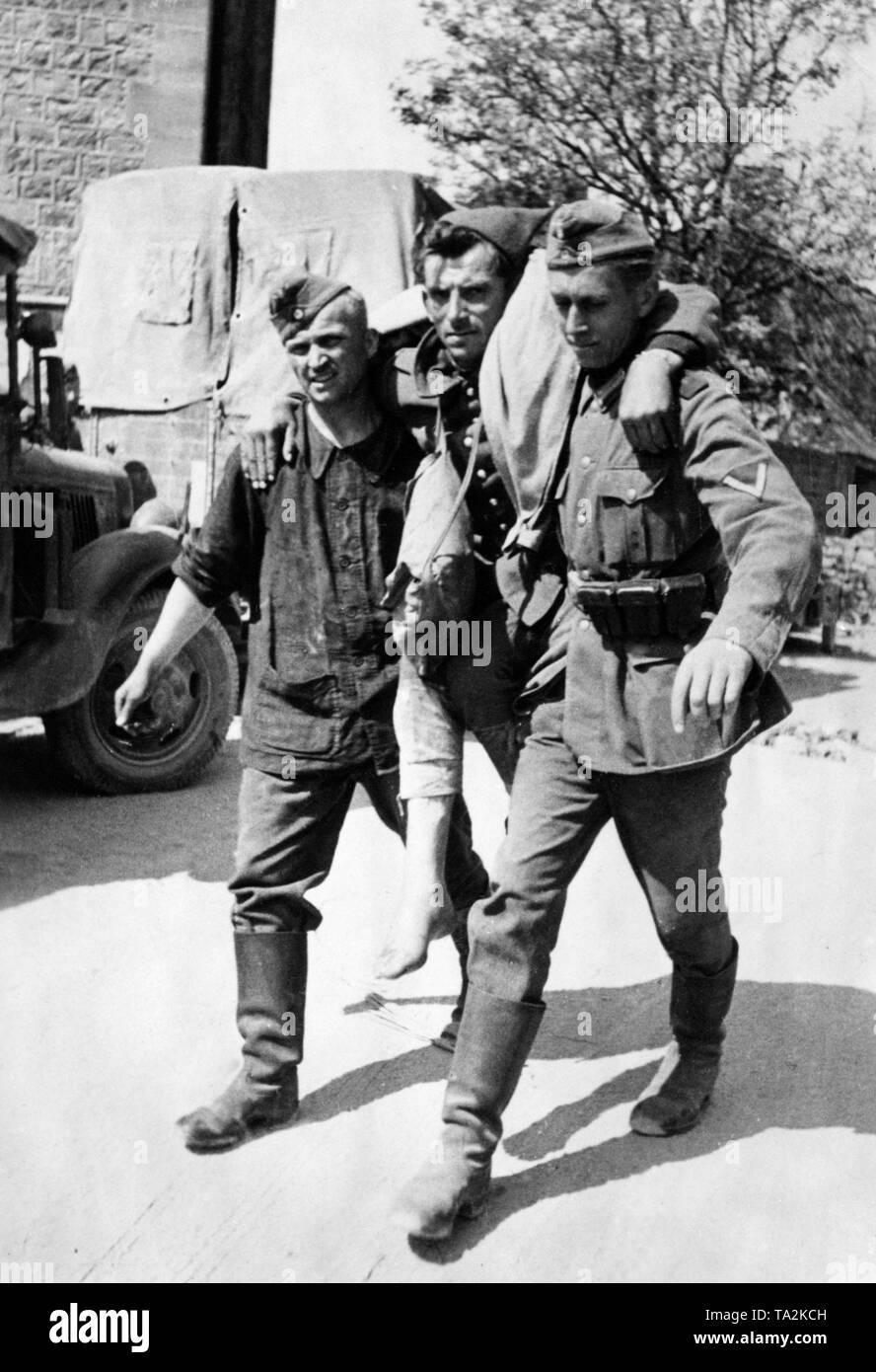 Two German soldiers carry a French prisoner of war to the dressing station. Photo. Brenner. Stock Photo