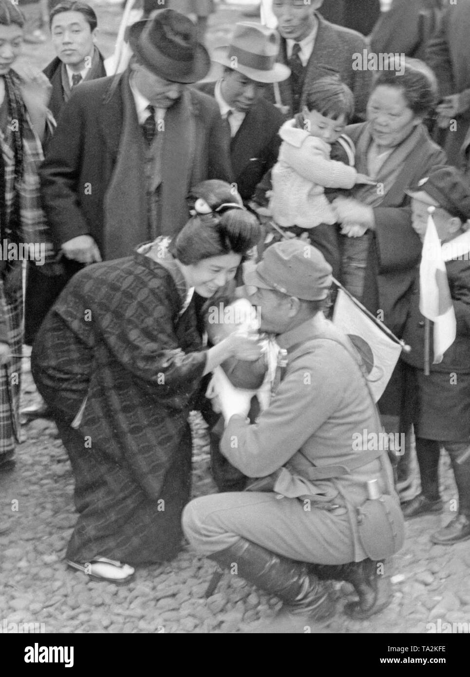 A soldier bids farewell to his wife and small child as he leaves to fight in the Second Japanese-Chinese War in China. All three are smiling. Stock Photo